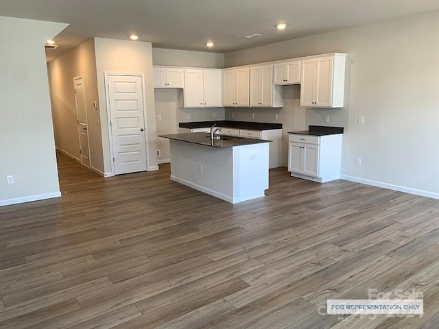 kitchen featuring white cabinets, dark hardwood / wood-style floors, sink, and an island with sink