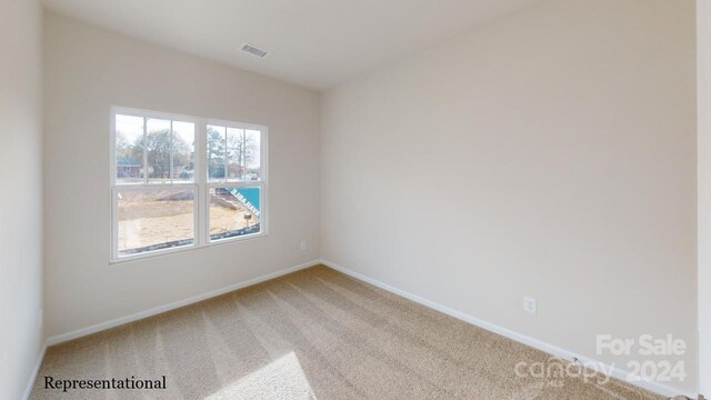 empty room featuring baseboards, visible vents, and light carpet