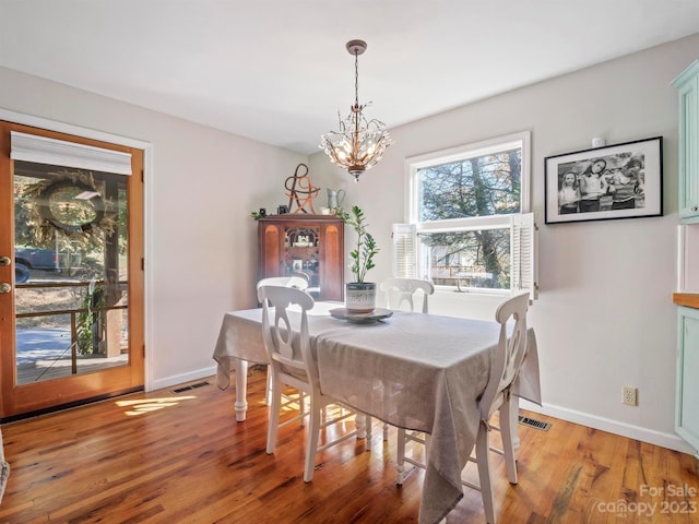 dining space with light wood-type flooring and an inviting chandelier