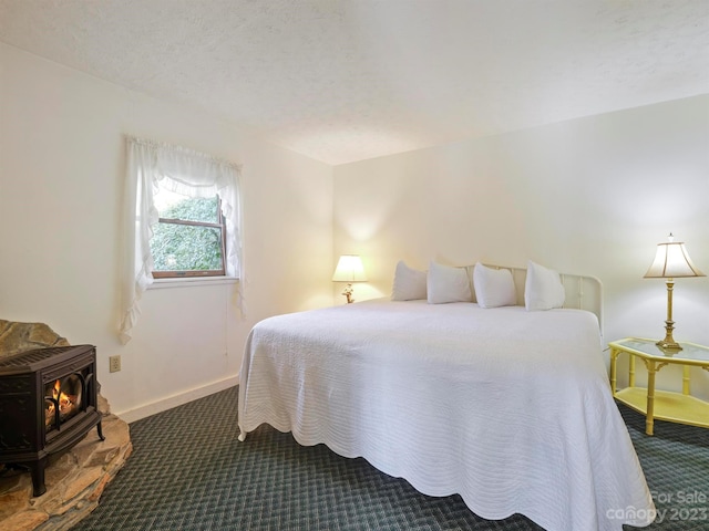 bedroom with a wood stove, a textured ceiling, and dark colored carpet