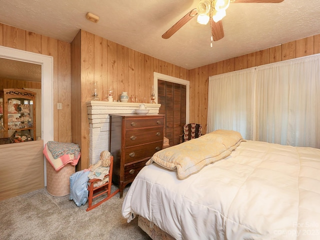 carpeted bedroom with ceiling fan, a closet, wood walls, and a textured ceiling