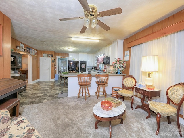 living room with dark tile flooring, wood walls, and ceiling fan