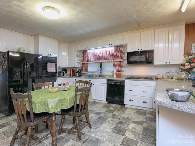 kitchen with sink, light tile floors, black appliances, and white cabinets