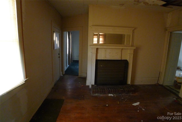 unfurnished living room featuring plenty of natural light and dark hardwood / wood-style flooring