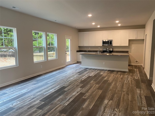 kitchen featuring white cabinets, a center island with sink, range, and dark hardwood / wood-style floors