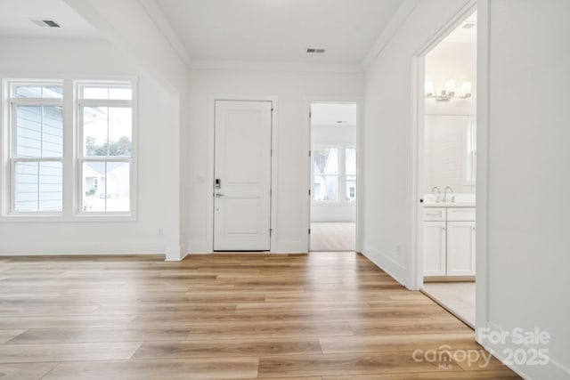 entryway with crown molding, sink, and light hardwood / wood-style floors