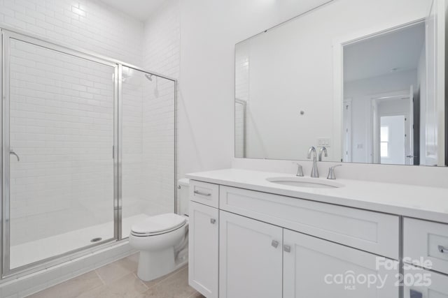 bathroom featuring tile patterned flooring, vanity, a shower with shower door, and toilet