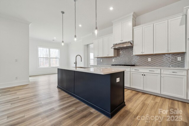 kitchen with sink, a center island with sink, white cabinets, and decorative light fixtures