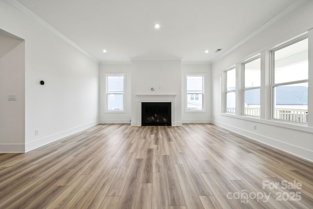 unfurnished living room featuring crown molding, plenty of natural light, and light hardwood / wood-style floors