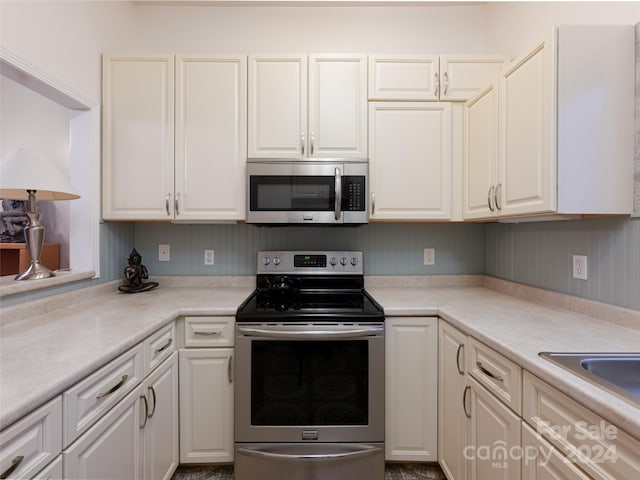 kitchen featuring stainless steel appliances, white cabinetry, and sink