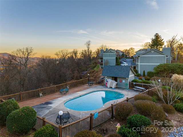 pool at dusk with an outbuilding and a patio