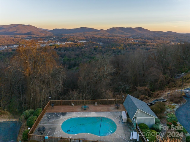 pool at dusk featuring a patio area and a mountain view