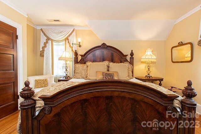 bedroom featuring crown molding, light hardwood / wood-style flooring, and lofted ceiling