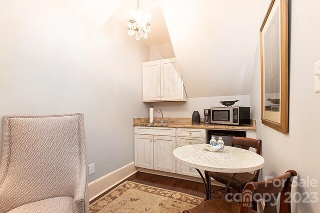 bathroom featuring wood-type flooring, sink, vaulted ceiling, and a notable chandelier