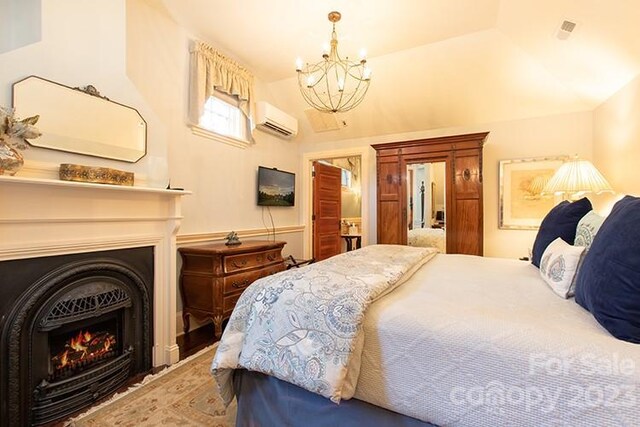 bedroom with a chandelier, a wall mounted air conditioner, and lofted ceiling