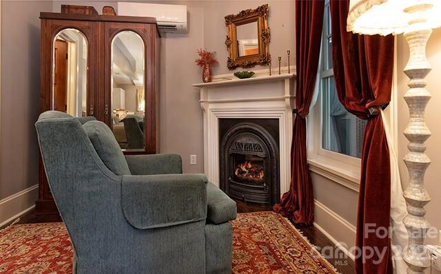 sitting room featuring dark wood-type flooring and a wall mounted air conditioner