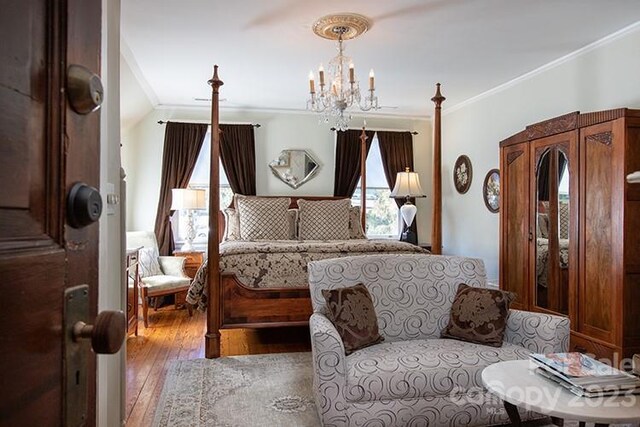 bedroom featuring crown molding, hardwood / wood-style floors, and a notable chandelier