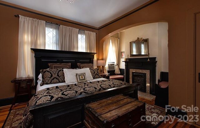 bedroom featuring hardwood / wood-style flooring, cooling unit, and crown molding