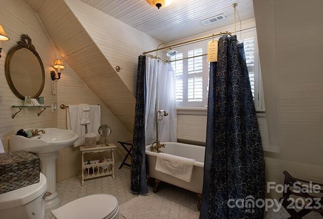 bathroom with shower / bath combo with shower curtain, toilet, and tile patterned flooring