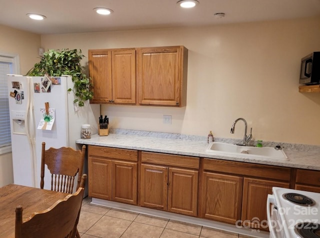 kitchen with sink, white fridge with ice dispenser, light stone counters, light tile patterned floors, and stove