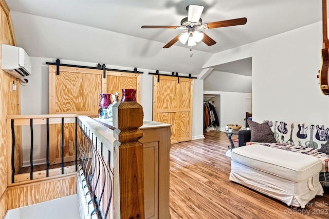 interior space featuring light hardwood / wood-style flooring, vaulted ceiling, an AC wall unit, and a barn door