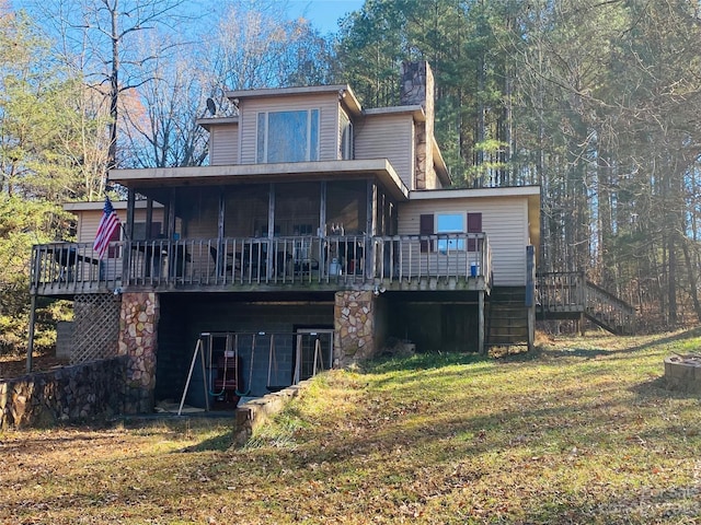 rear view of house with stairway, a yard, a wooden deck, and a sunroom