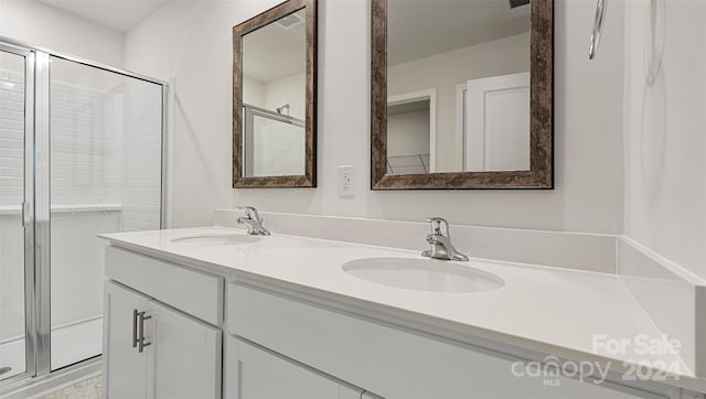 bathroom featuring a shower with door and dual vanity