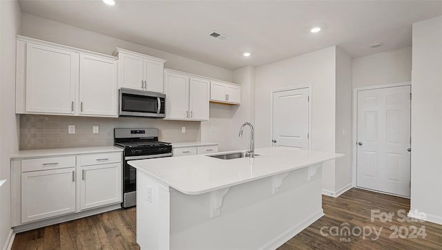 kitchen with sink, appliances with stainless steel finishes, a kitchen island with sink, and dark hardwood / wood-style floors