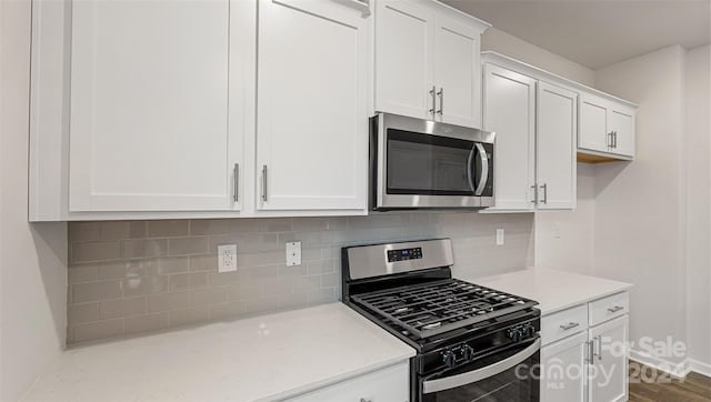 kitchen featuring backsplash, stainless steel appliances, white cabinets, and hardwood / wood-style flooring