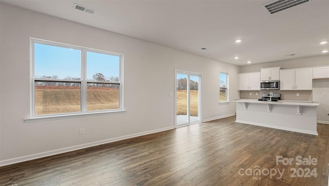 kitchen with a kitchen island with sink, a breakfast bar, white cabinets, range, and dark hardwood / wood-style floors