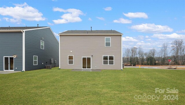 back of house with central AC unit, a lawn, and a patio area