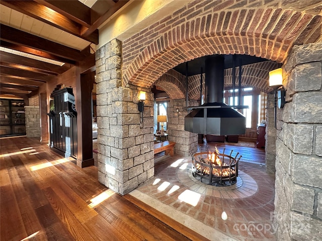 461 Spice Bottom Trl, Banner Elk, NC 28604 - interior space featuring decorative columns, arched walkways, beamed ceiling, a wood stove, and hardwood / wood-style flooring