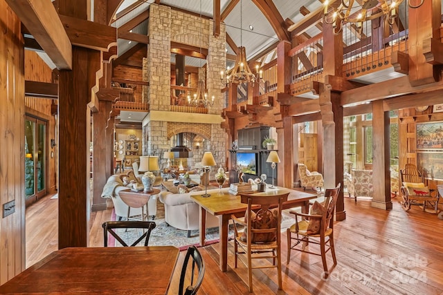 dining room featuring high vaulted ceiling, beamed ceiling, wooden walls, and hardwood / wood-style flooring