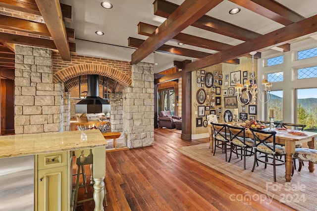 dining area featuring dark wood-type flooring, bar, and beam ceiling