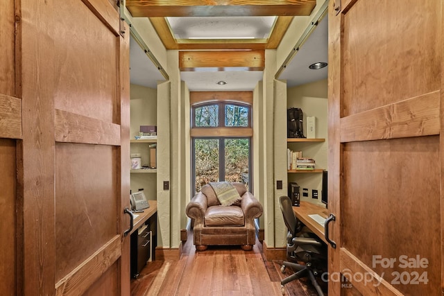 living area with beamed ceiling, a barn door, and light hardwood / wood-style flooring