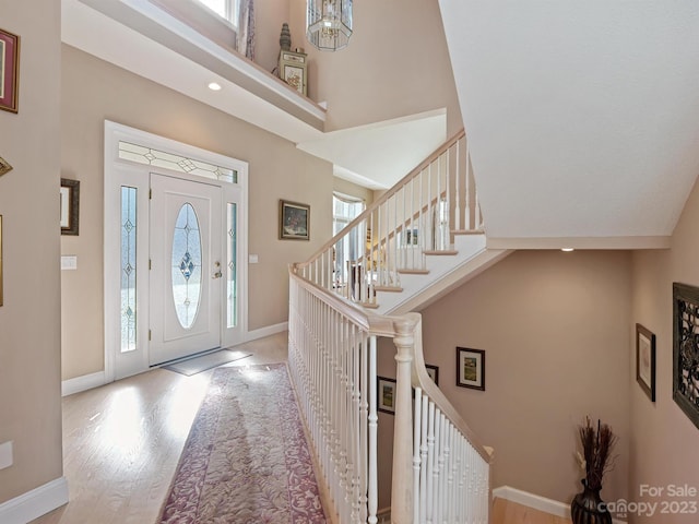 entrance foyer with high vaulted ceiling and light hardwood / wood-style flooring