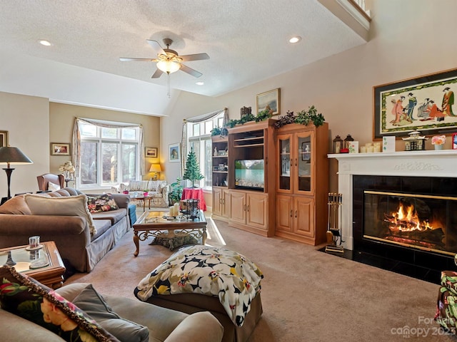 living room featuring a tile fireplace, carpet floors, a textured ceiling, ceiling fan, and lofted ceiling