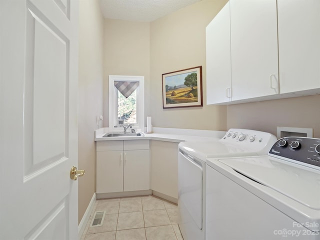 laundry area with washer and dryer, cabinets, sink, a textured ceiling, and light tile patterned flooring