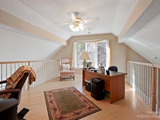 office area with light hardwood / wood-style floors, lofted ceiling, ceiling fan, and a textured ceiling