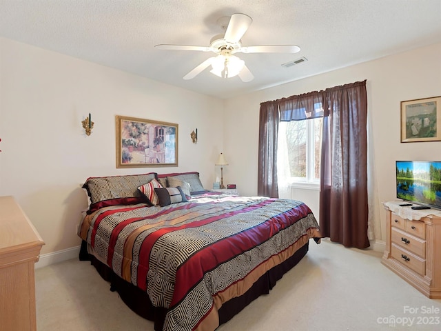 bedroom with ceiling fan, light carpet, and a textured ceiling