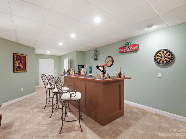 bar featuring a drop ceiling and light carpet