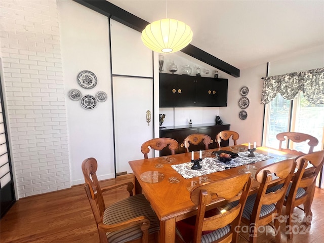 dining area featuring hardwood / wood-style floors, vaulted ceiling with beams, and brick wall