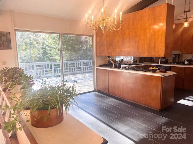 kitchen with dark tile flooring, pendant lighting, and an inviting chandelier