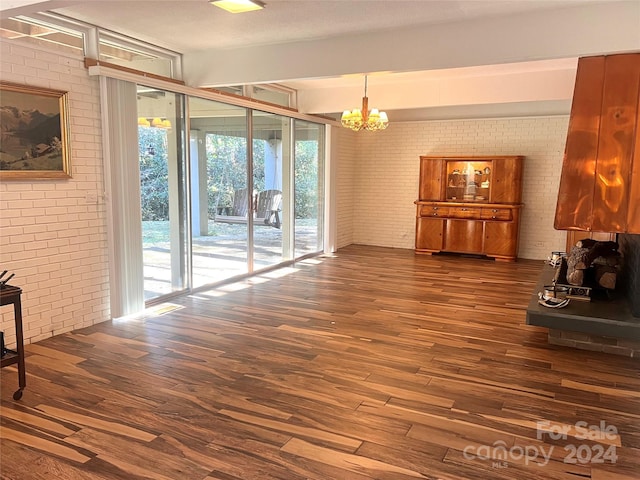 living room featuring dark hardwood / wood-style flooring, brick wall, and a chandelier