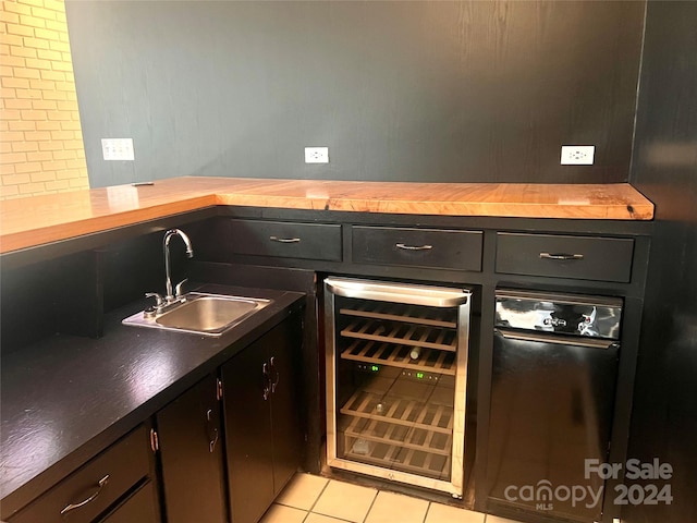 interior space with butcher block countertops, sink, wine cooler, light tile flooring, and tasteful backsplash