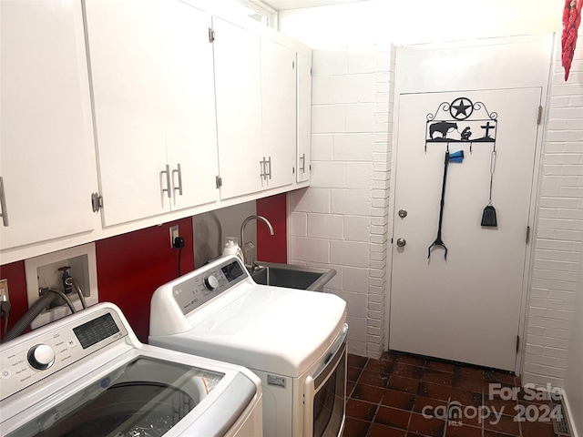 clothes washing area with washing machine and dryer, washer hookup, sink, dark tile flooring, and cabinets