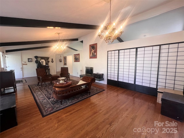 living room with a chandelier, a large fireplace, lofted ceiling with beams, and wood finished floors