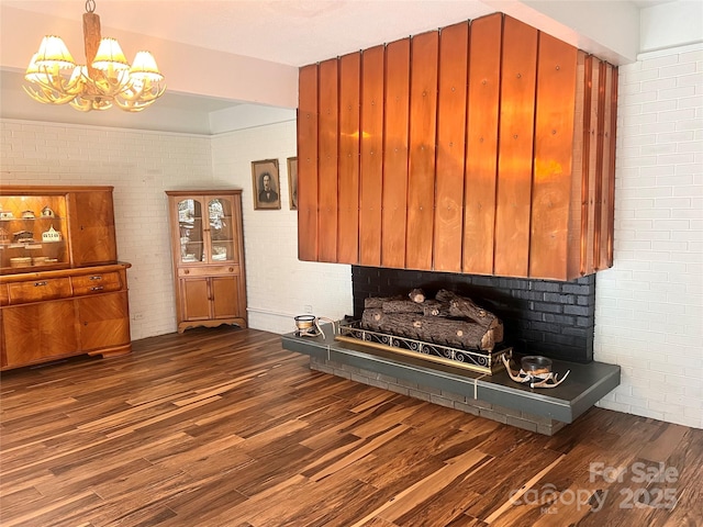 interior space featuring an inviting chandelier, brick wall, and dark wood finished floors