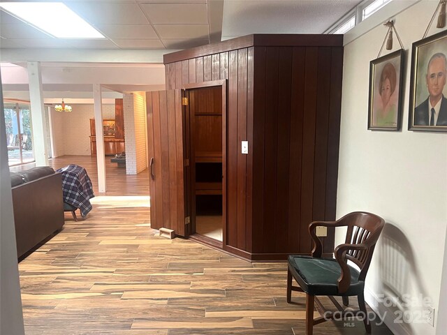 hall featuring light wood-style flooring and a drop ceiling