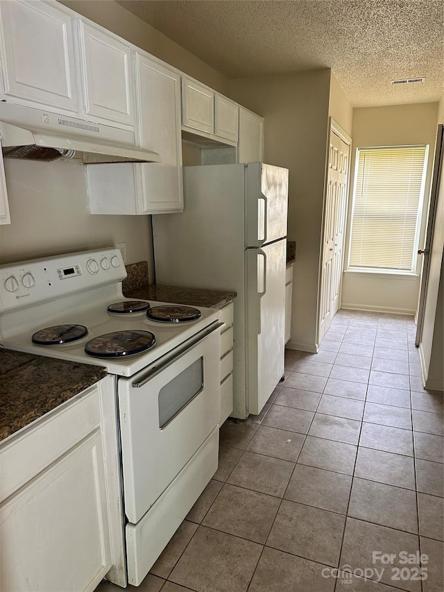 kitchen featuring a textured ceiling, white appliances, white cabinetry, and light tile patterned flooring